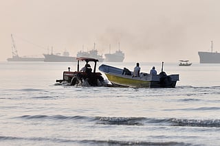 A tractor tows a small boat through shallow water as cargo ships and industrial vessels are anchored in the Strait of Hormuz off Bandar Abbas, Iran, Monday, June 1, 2026.  