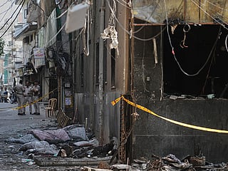 Policemen stand guard near a restaurant and hotel building that caught fire in New Delhi, India