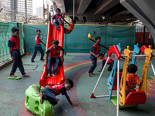 This photograph taken on May 18, 2026 shows children in a play area at the "Signal Shala", or traffic signal school, under a bridge in Mumbai. Beneath a busy flyover in India's financial capital Mumbai, a row of pastel-coloured shipping containers houses an unlikely school serving some of the city's most marginalised children. (Photo by Punit PARANJPE / AFP)