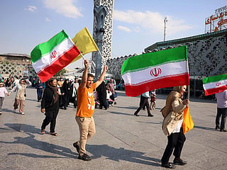People wave Iran's national flags during a rally in support of the country's supreme leader Mojtaba Khamenei.
