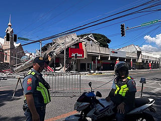 Police gather in front of a collapsed Jollibee fast food restaurant after an 7.8 magnitude earthquake in General Santos City.