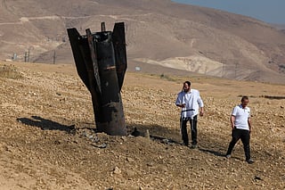 Two men examine a fallen rock half-buried in the ground on the outskirts of Jericho on June 8, 2026, following Iranian and Iran-backed Houthi rebel attacks.