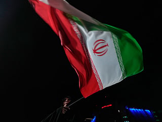 A pro-government Iranian demonstrator waves her country's flag in a gathering in Tehran, Iran.