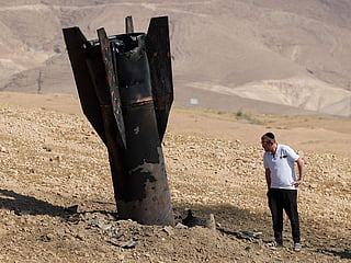 A man checks a fallen rocket half-buried in the ground on the outskirts of Jericho on June 8, 2026.