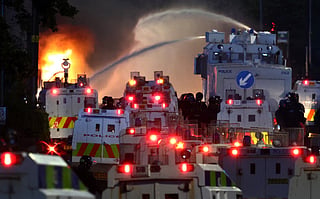 Police use a water cannon as they block the road from protesters (behind) leading to a hotel previously believed to house migrants, on Antrim Road in Glengormley, north of Belfast, Northern Ireland, on June 10, 2026.