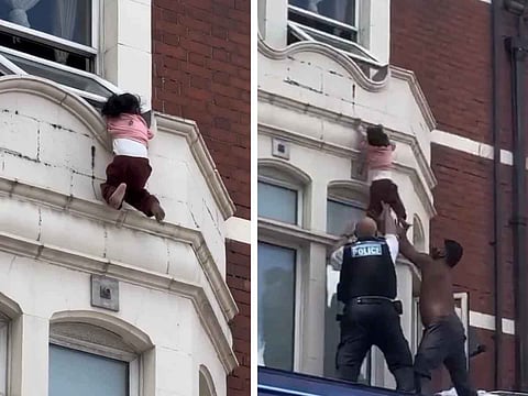 Moments of terror and relief: A child hangs from a window ledge above a busy East London street before being rescued by a police officer and a member of the public.
