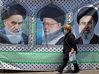 A woman walks past a banner bearing the images of the late founder of the Islamic Revolution supreme leader Ayatollah Ruhollah Khomeini (L), the late Iranian supreme leader Ali Khamenei and his son, the current supreme leader Mojtaba Khamenei (R), erected along a street at the Vanak Square in Tehran. 
