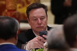 FILE - Elon Musk uses his phone during a state dinner for President Donald Trump and Chinese President Xi Jinping at the Great Hall of the People on Thursday May 14, 2026, in Beijing. (AP Photo/Mark Schiefelbein, File)