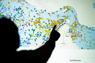 A photo illustration taken in Nicosia on May 4, 2026, shows a person in front of a large screen displaying vessel movements in the Strait of Hormuz on a ship-tracking website.