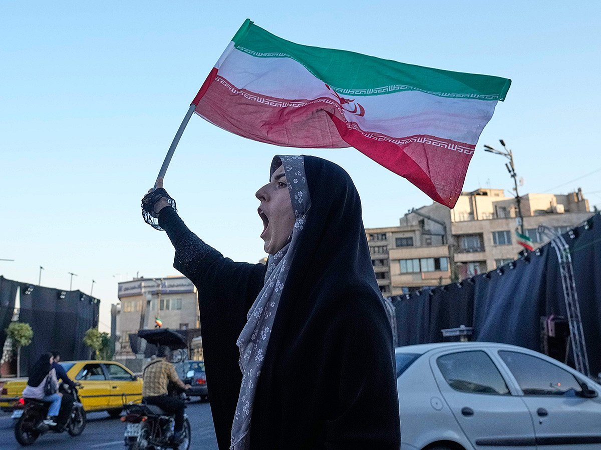 A woman waves an Iranian flags as she chants slogans against Iran and US talks at the Islamic Revolution square in Tehran.