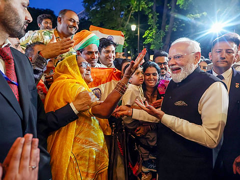 India Prime Minister Narendra Modi interacts with a woman as he receives a warm welcome from the Indian community on arrival, in Paris on Wednesday. 