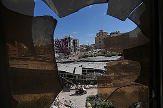Buildings damaged by Israeli strikes are seen through shattered glass from the Jabal Amel Hospital in the southern port city of Tyre, Lebanon, Thursday, June 18, 2026. 