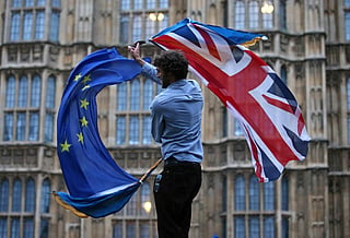 A man waves both a Union flag and a European flag together on College Green outside The Houses of Parliament at an anti-Brexit protest in central London on June 28, 2016.