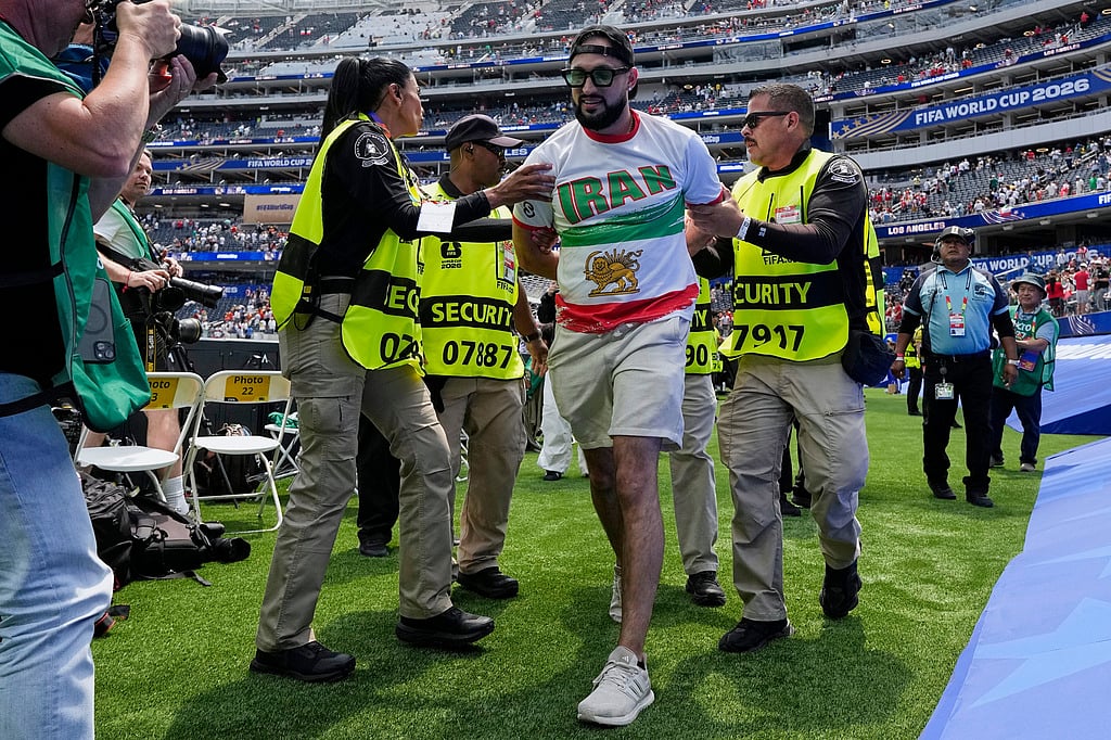 An Iranian fan is removed from the pitch by security at the end of the World Cup Group G soccer match between Belgium and Iran in Inglewood, Calif., near Los Angeles, Sunday, June 21, 2026. (AP Photo/Gregory Bull)