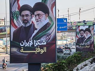 Cars and motorbikes drive past billboards showing Iran’s new Supreme Leader Ayatollah Mojtaba Khamenei (L) and his late father Ali Khamenei (R), with the slogan “Thank you, loyal Iran,” erected along the highway leading to Rafic Hariri International Airport in Beirut on June 22, 2026. 