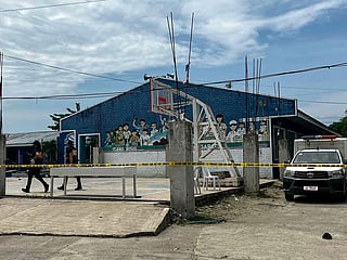 Police investigators walk in front of the school entrance after a shooting incident at a high school compound in Tacloban City.
