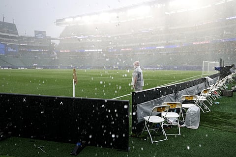 A photographer wears a raincoat as the 2026 World Cup Group I football match between France and Iraq is suspended due adverse weather at the Philadelphia Stadium in Philadelphia on June 22, 2026.