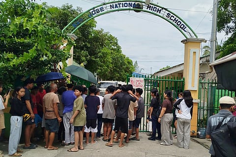 Students and their parents wait for permission from school authorities to enter the school compound at the gate of San Jose High School in Tacloban City, Leyte province in the central Philippines on June 23, 2026, a day after a shooting incident.