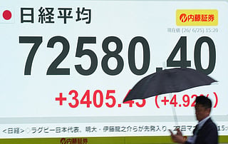 A man walks past an electronic quotation board displaying the Nikkei Stock Average on the Tokyo Stock Exchange along a street in Tokyo on June 25, 2026.