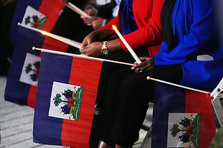 FILE - People hold Haitian flags and candles during a vigil at the Little Haiti Cultural Complex after a federal judge blocked the Trump administration from ending temporary immigration status, or TPS, for Haitians, Feb. 3, 2026, in North Miami. (AP Photo/Lynne Sladky, File)