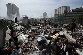 Locals walk amid rubble following a twin earthquake in Caraballeda, La Guaira state, about 40 km northeast of Caracas, on June 25, 2026.