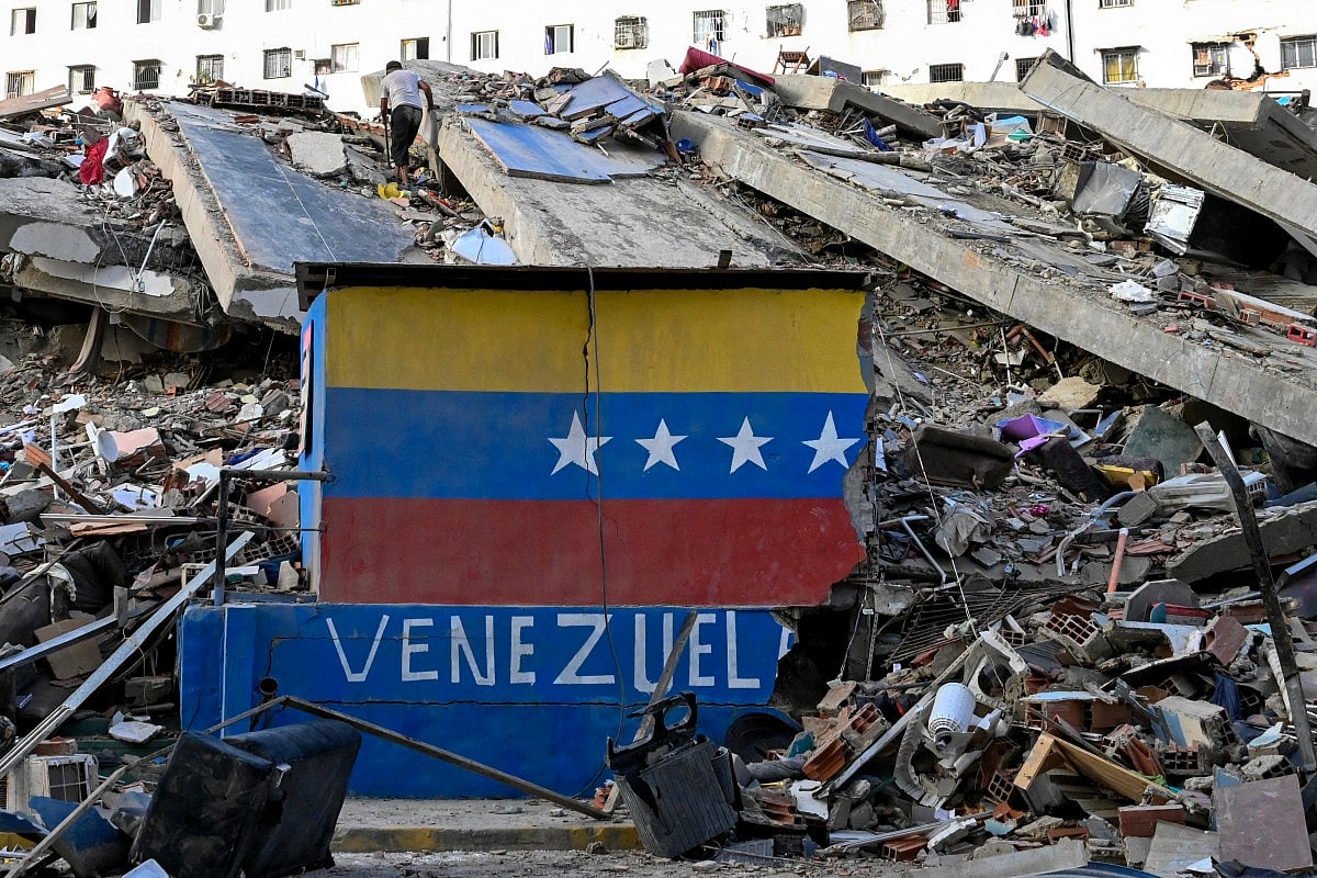 A Venezuelan flag is seen painted on a damaged wall amid the rubble of a collapsed building following earthquakes in Caraballeda, La Guaira state, Venezuela, on June 26, 2026.