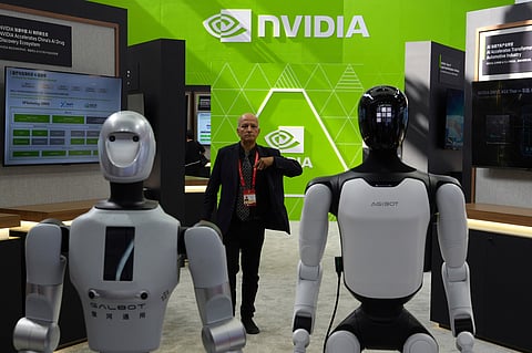 A worker stands near robots at the Nvidia booth during the China International Supply Chain Expo in Beijing on June 22, 2026. (AP Photo/Ng Han Guan)