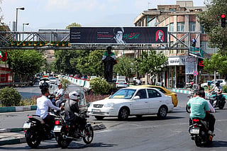 Motorists ride motorcycles past a mourning billboard depicting Iran's slain supreme leader Ali Khamenei, who was killed in a strike on the first day of the US-Israeli war against the Iran on February 28, along Hafte Tir Square in Tehran on June 30, 2026 ahead of his public funeral.