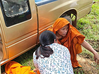Nurse Wiwat Naonoi assisting an injured Buddhist monk after a collision between their roadside procession and a pickup truck driven by an 11-year old.
