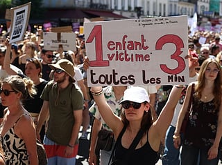 A demonstrator brandishes a placard reading '1 child victim every 3 minutes' during a rally against sexual violence against women and children called by the Women's Foundation in Paris, on July 4, 2026.