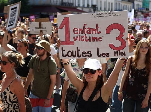 A demonstrator brandishes a placard reading '1 child victim every 3 minutes' during a rally against sexual violence against women and children called by the Women's Foundation in Paris, on July 4, 2026.