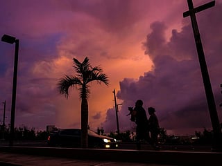 People walk along a street at sunset ahead of the arrival of the forecasted Super Typhoon Bavi in Guam, Northern Mariana Islands, on July 4, 2026.