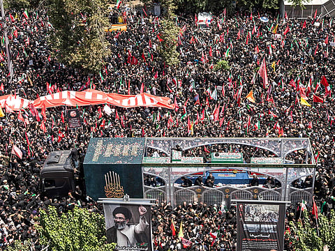 Crowds of mourners surround the convoy carrying the coffins of Iran's slain supreme leader Ali Khamenei and members of his family during a funeral procession near Azadi Square in Tehran on July 6, 2026. 