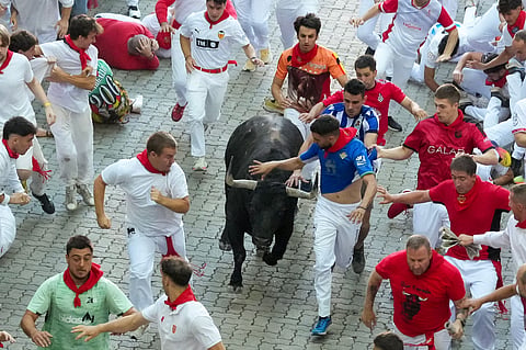 Participants run ahead of bulls from the Fuente Ymbro bull ranch during the first running of the bulls of the San Fermin festival in Pamplona, northern Spain, on July 7, 2026. Thousands of people every year attend the week-long festival and its famous 'encierros', or running of the bulls, in which six bulls are released at 8:00 a.m. evey day to run from their corral to the bullring through the narrow streets of the old town over an 850 meters (yards) course while runners ahead of them try to stay close to the bulls without falling over or being gored.