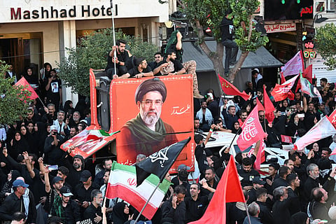 Mourners gather around a portrait of Iran's Supreme Leader Mojtaba Khamenei ahead of the funeral procession for his father, Ali Khamenei, in Mashhad. Analysts say Iran's leadership is balancing pressure from hardliners seeking revenge with voices urging diplomacy.