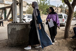 Palestinian women make their way to university as they walk past a closed Israeli military check-point outside Deir Ammar in the Israeli-occupied West Bank on July 9, 2026, after a five-month-old baby reportedly died after his family was delayed by Israeli forces from passing the check-point and reaching a hospital.