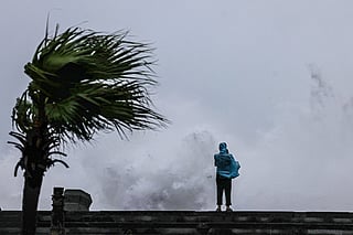 A person looks on as large waves crash against the coast as Typhoon Bavi passes off northeastern Taiwan, in Keelung on July 11, 2026.