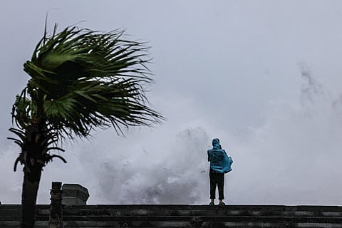 A person looks on as large waves crash against the coast as Typhoon Bavi passes off northeastern Taiwan, in Keelung on July 11, 2026.