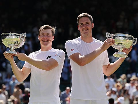 Britain's Henry Patten and Finland's Harri Heliovaara pose with their trophies after winning against El Salvador's Marcelo Arevalo and Croatia's Mate Pavic during their men's doubles final of the 2026 Wimbledon Championships at The All England Lawn Tennis and Croquet Club in Wimbledon, southwest London, on July 11, 2026.