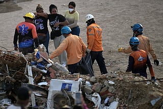 Relatives react as rescuers carry a body bag recovered from the rubble of the collapsed Obras del Poder Popular (OPP) building in Caraballeda, La Guaira state, Venezuela, on July 12, 2026, following twin earthquakes that struck the region.