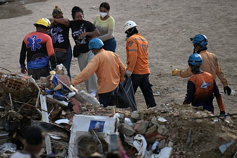 Relatives react as rescuers carry a body bag recovered from the rubble of the collapsed Obras del Poder Popular (OPP) building in Caraballeda, La Guaira state, Venezuela, on July 12, 2026, following twin earthquakes that struck the region.