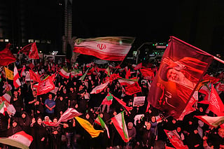 Pro-government demonstrators wave Iranian and religious flags in a gathering commemorating the late Iranian Supreme Leader Ayatollah Ali Khamenei, shown in a flag at right, at a square in Tehran, Saturday, July 11, 2026. 