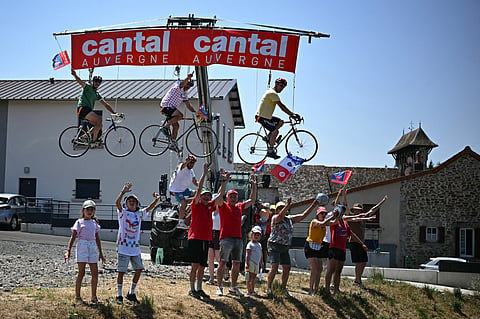 Spectators ride bicycles hanging from a telehandler along the race route at the start of the 10th stage of the 113th edition of the Tour de France cycling race.
