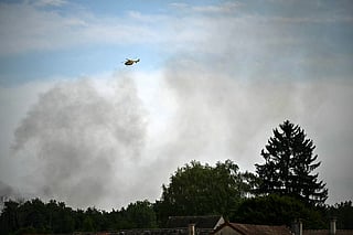 This photograph shows a firefighter aircraft flying near a plume of smoke from a fire in the Fontainebleau Forest, in Noisy-sur-Ecole, in the Paris' Ile-de-France region on July 16, 2026.