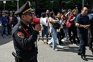 A member of the Secretariat of Citizen Security uses a megaphone to give instructions to personnel evacuated from several buildings following a preventive evacuation in Mexico City on July 17, 2026, after a 7.3-magnitude earthquake struck southern Mexico and parts of Central America.
