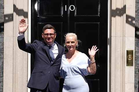 Britain's new Prime Minister Andy Burnham and his wife Marie-France van Heel wave as they arrive at 10 Downing Street in London, on Monday, July 20, 2026.