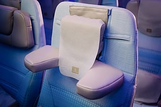 The image shows the world's first U-Dream headrest installed on an Emirates Economy Class seat, highlighting the adjustable side cushions designed to provide personalised neck and head support.