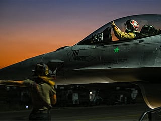 A US Air Force fighter pilot performs pre-flight checks on an F-16 fighter jet.