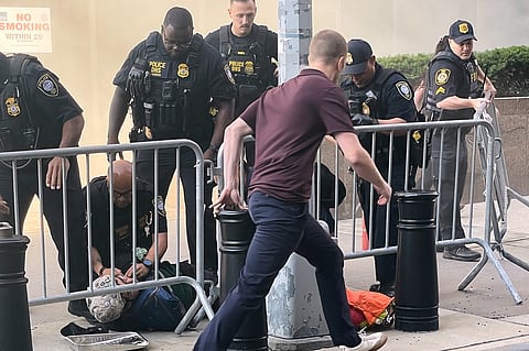 In this photo provided by Robert Sullivan several officers surround a person on the ground near the site of a fire at 26 Federal Plaza in lower Manhattan, Monday, July 20, 2026, in New York. (Robert Sullivan via AP)