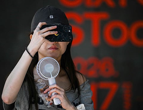 A woman uses a portable fan to cool herself down in Tokyo.
